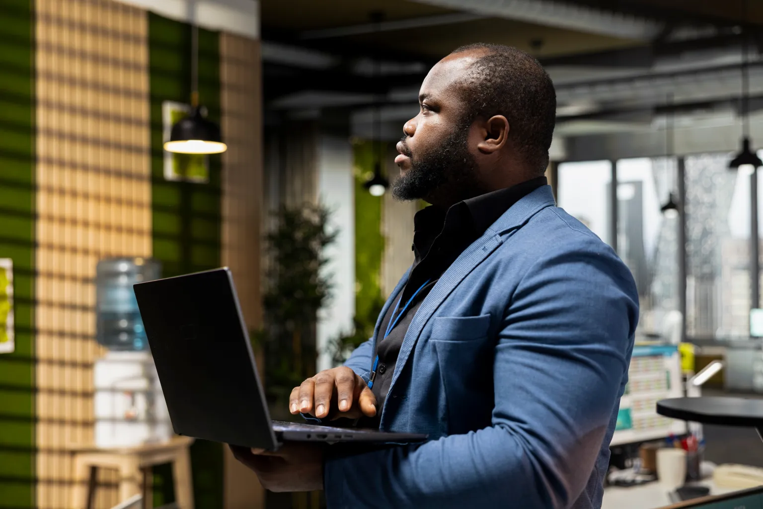 Profissional de blazer azul segura um notebook aberto em um escritório moderno