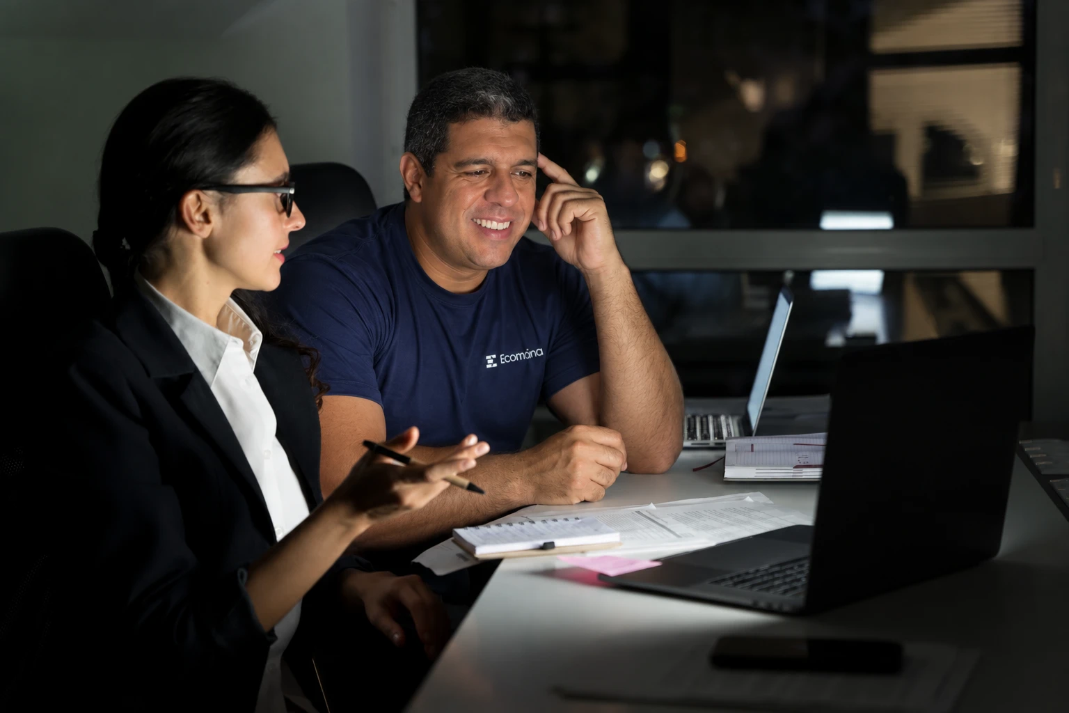 Geraldo Durães, fundador da EcomSmart, e uma colega analisam resultados no notebook