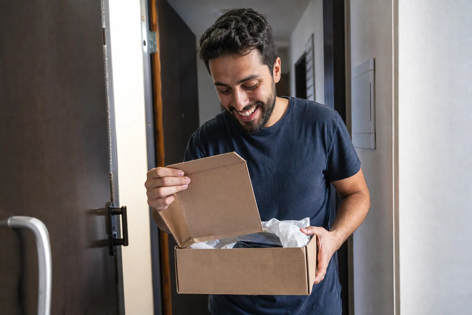 Cliente recebe uma encomenda na porta de casa e sorri ao abrir a caixa