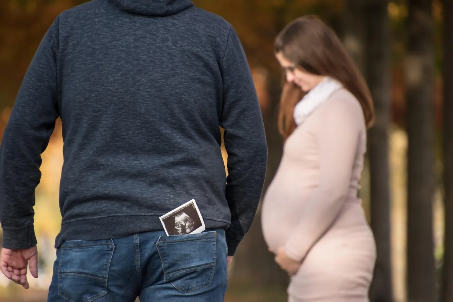 Casal fotografa plaquinha com o celular na varanda para preparar o post de anúncio de gravidez