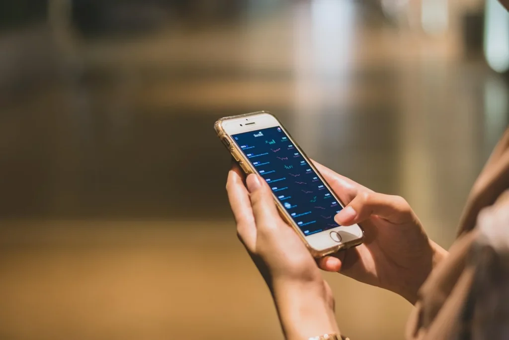 Dona de loja de moda fitness confere no celular a prévia de um anúncio pago do Instagram no estoque