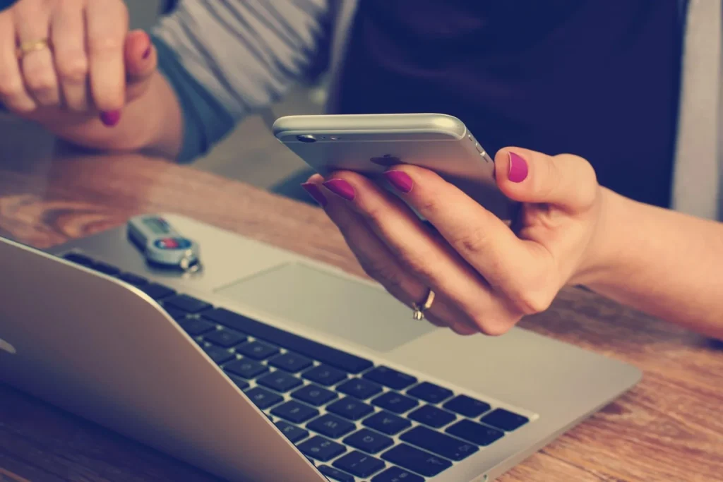 Dona de loja virtual de cosméticos confere pedidos impressos e o celular no estoque