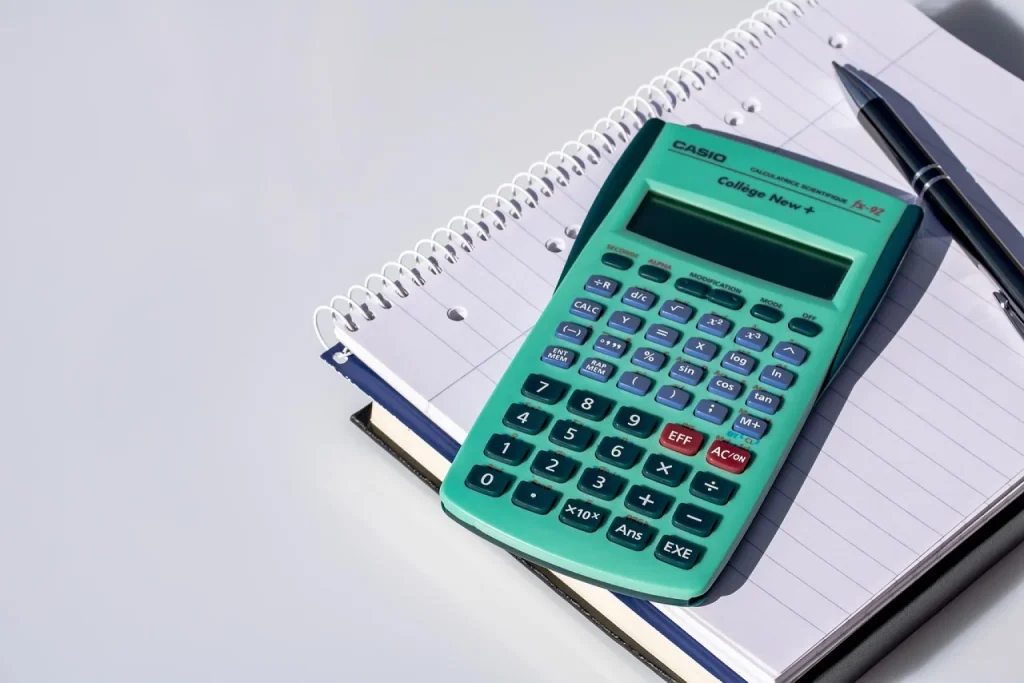 Dona de loja virtual confere o extrato de taxas do cartão com calculadora na mesa de embalagem