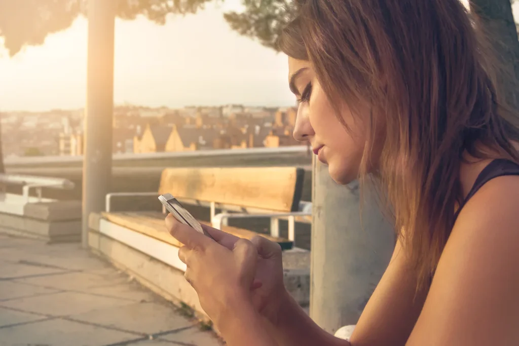Dona de loja virtual de cosméticos confere mensagens automáticas no celular no estoque da loja