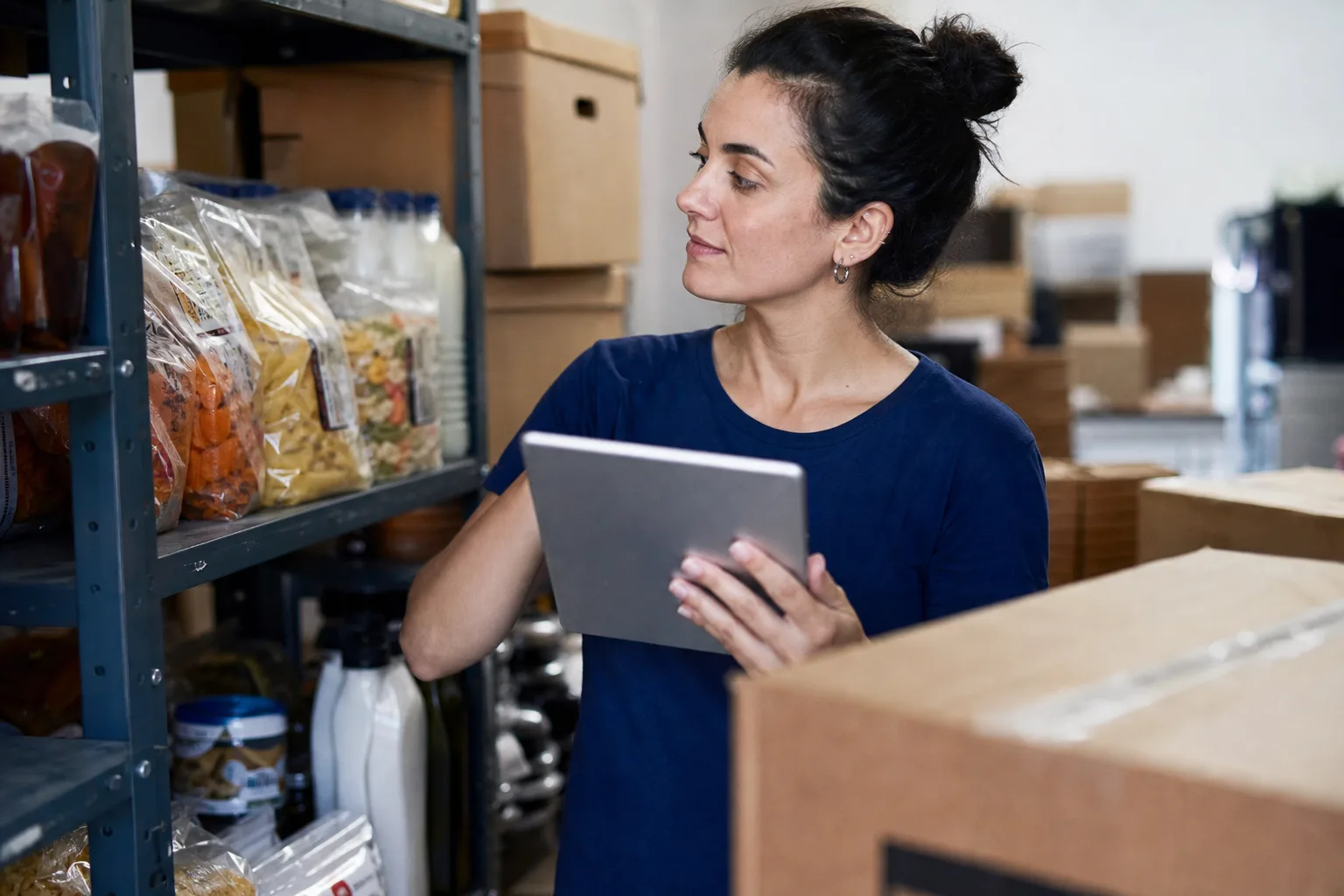 Funcionário conferindo pequenos lotes de alimentos e produtos de revenda no estoque de uma loja virtual