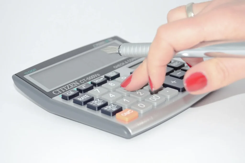 Dona de loja virtual confere fatura e calculadora na bancada de embalagem, cercada de caixas prontas para envio